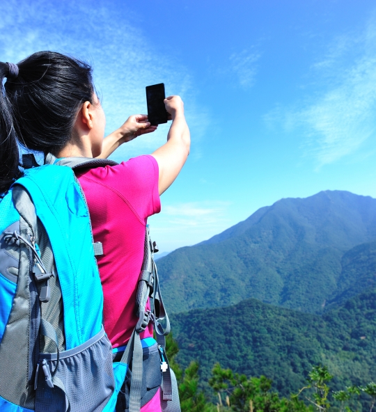 hiking asian woman taking photo with smart phone on mountain peak