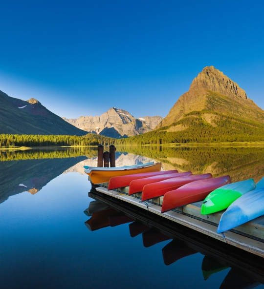 A group of canoes resting at the dock deck at Many Glacier Swiftcurrent Lake at Glacier National Park. Many Glacier National Park, Montana, a scenic tourist destination in the northwest region of United States. Photographed in horizontal format.